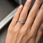 Close-up of a hand wearing a diamond ring with a blurred background