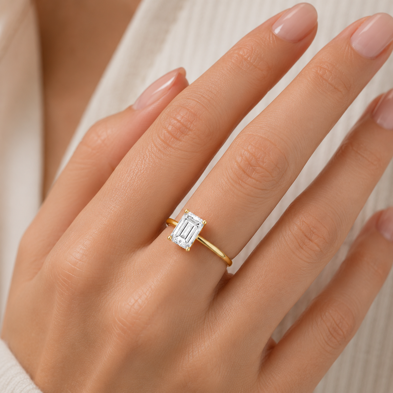 Gold ring with a diamond on a hand against a neutral background