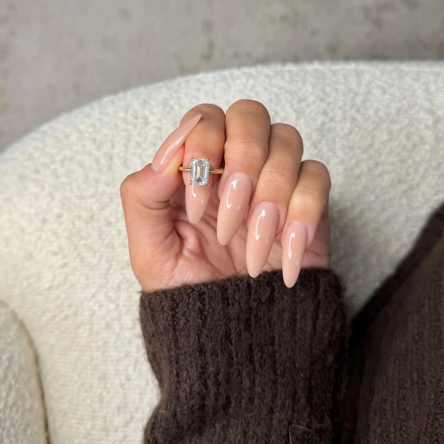 Hand wearing a diamond ring with a neutral background