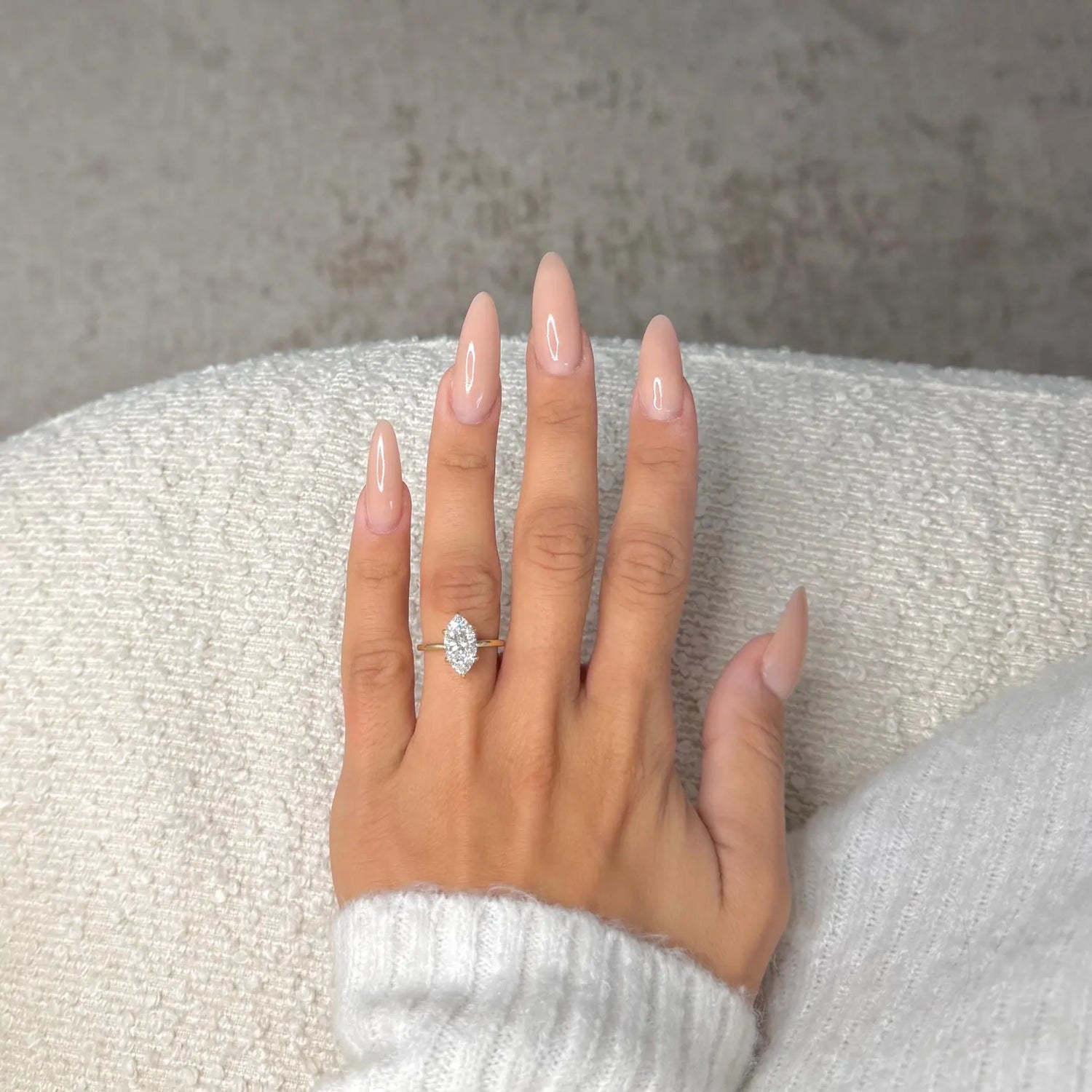 Hand wearing a diamond ring on a textured surface