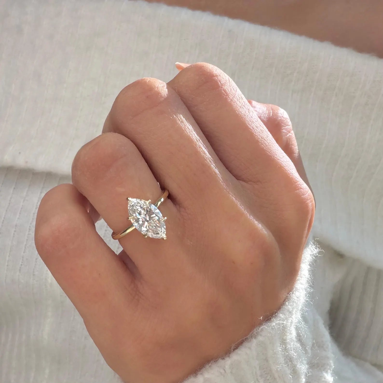 Hand wearing a diamond ring with a soft background