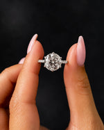 Diamond ring held between fingers against a black background