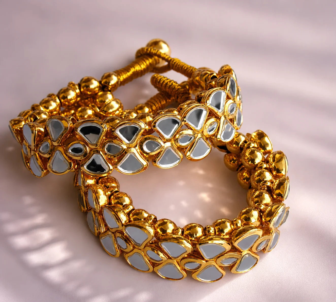 Gold bracelet with reflective stones on a light background