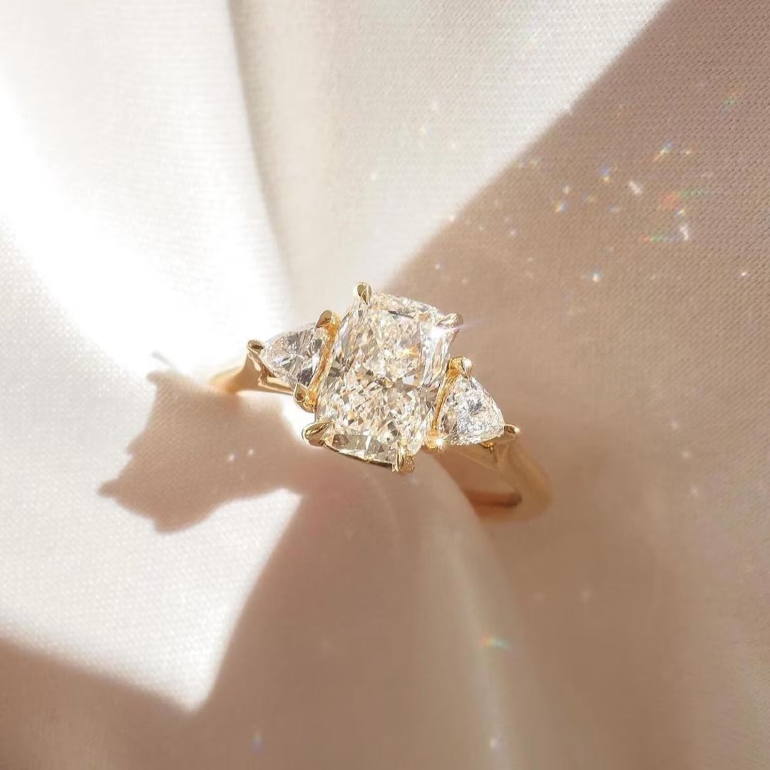 Gold ring with three diamonds on a soft beige background