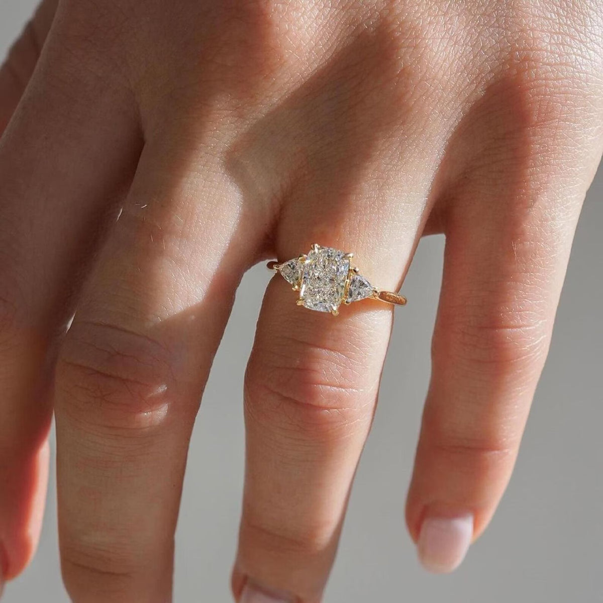 Rose gold ring with a diamond on a hand against a neutral background