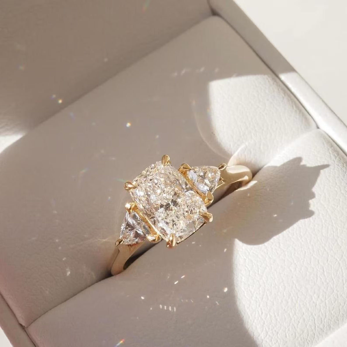 Gold ring with a large diamond and smaller triangles on a light background